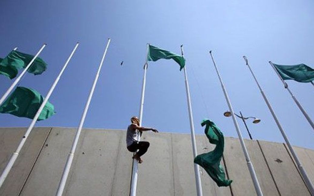 Лівійська Арабська Джамахірія, Тріполі. Лівійські повстанці зривають зелені державні прапори на площі Абу-Салім у Тріполі. Опозиційні сили оголосили про переведення їхнього керівництва до столиці, а ООН погодилася розморозити 1,5 мільярди доларів Каддафі, щоб направити їх для надання гуманітарної допомоги Лівії. / © AFP
