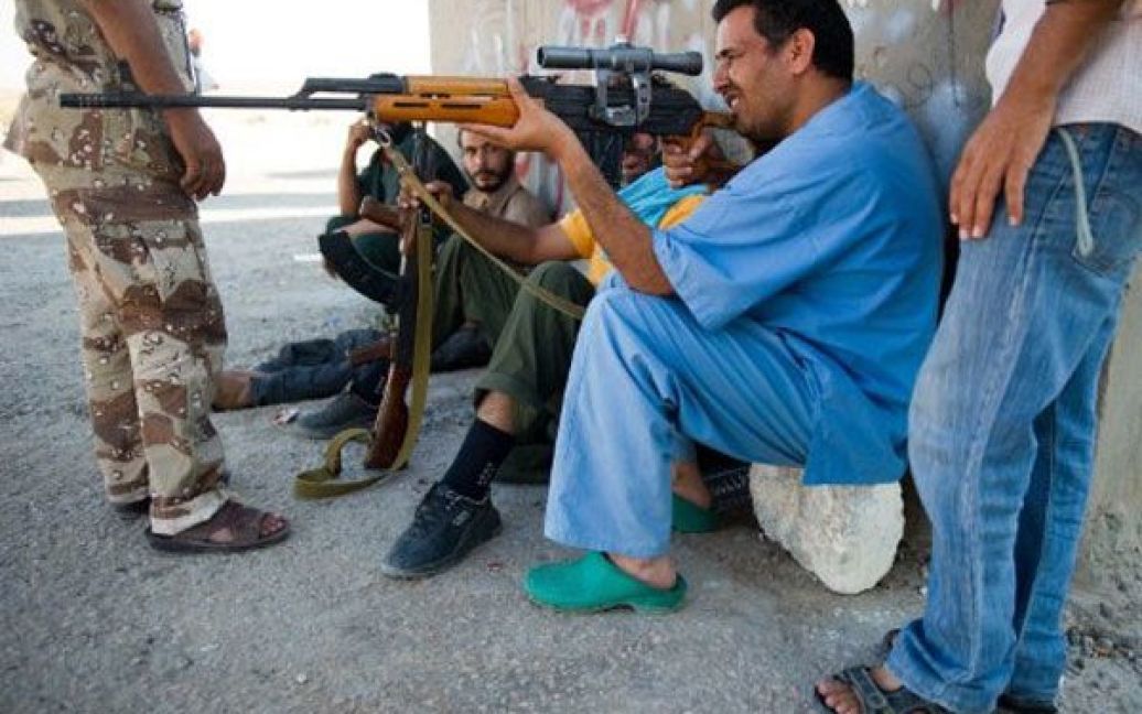 Лівійська Арабська Джамахірія, Бані Валід. Лікар роздивляється гвинтівку на контрольно-пропускному пункті поблизу міста Бані Валід. Силам Муаммара Каддафі було запропоновано залишити цей район, НАТО продовжує здійснювати удари по об&#039;єктах. / © AFP