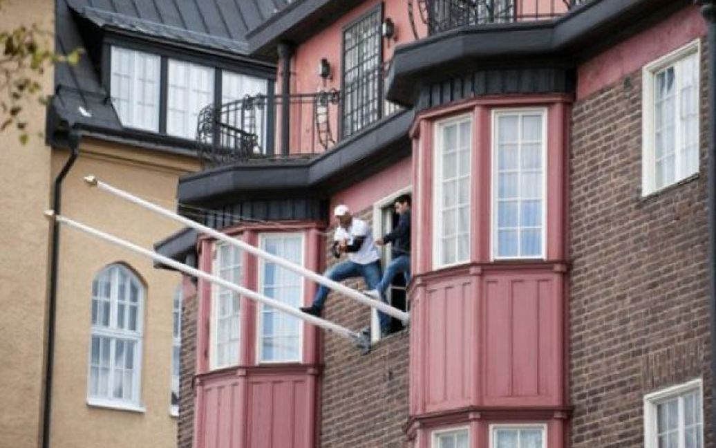 Швеція, Стокгольм. Група активістів намагається зірвати прапор з флагштоку на стіні посольства Лівії у Стокгольмі. Кілька молодих людей увірвалися до посольства та погрожували вистрибнути з вікна. Поліція вважає, що порушники були учасниками анти-лівійської демонстрації. / © AFP