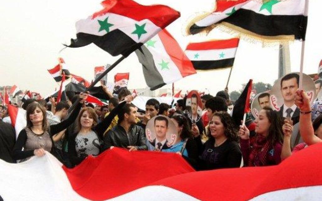 Сирія, Дамаск. Десятки тисяч людей з сирійськими прапорами та фотографіями президента взяли участь у мітингу на підтримку лідера Сирії Башара аль-Асада, який провели на площі Омейядів в центрі Дамаску. / © AFP