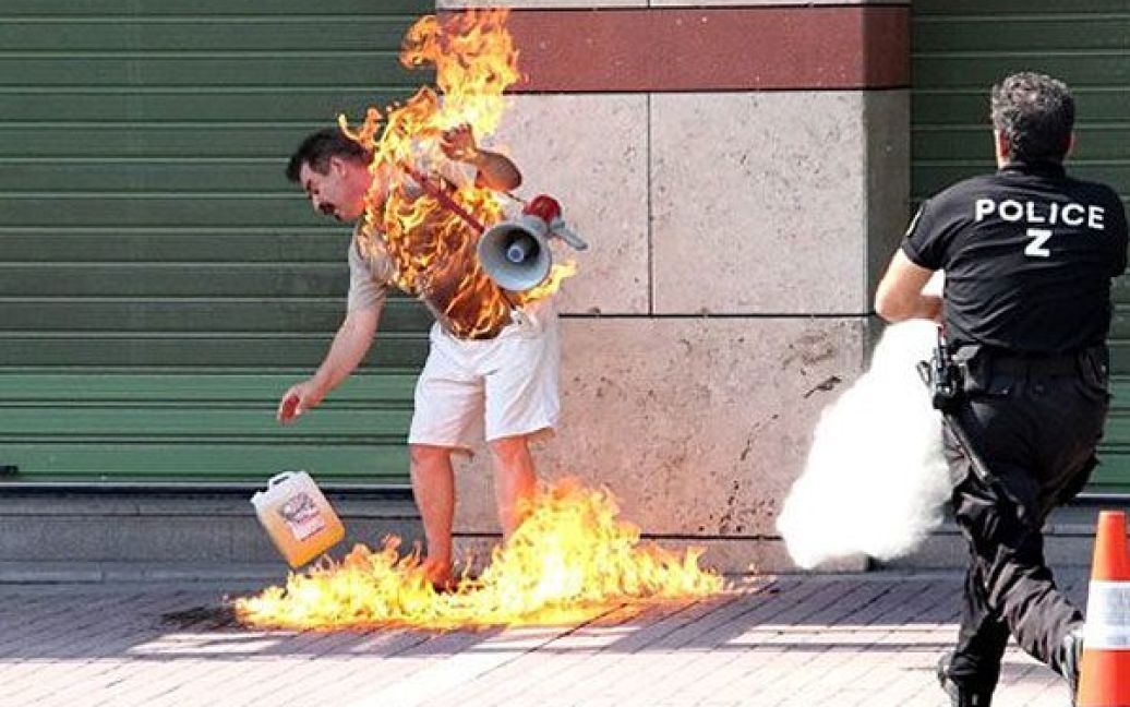 Греція, Салоніки. Поліцейський поспішає, щоб загасити 55-річного чоловіка, який підпалив себе перед відділенням банку на знак протесту проти уряду, банків і політичних партій. Чоловіка, який здійснив спробу самоспалення через фінансові проблеми госпіталізували з опіками. / © AFP