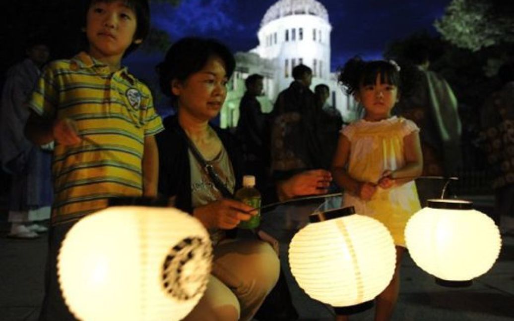 Японія, Хіросіма. Жінка із дітьми запалила ліхтарики поблизу Меморіального центру жертв атомного бомбардування. Шостого серпня Японія відзначить 66-ту річницю першої в світі атомної атаки. / © AFP