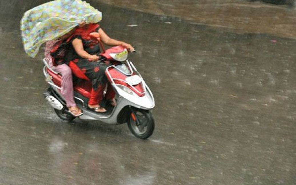 Індія, Хайдарабад. Індійці їдуть через зливу у місті Хайдарабад. Мусонні дощі, які є дуже важливими для щорічного врожаю, спричинили повені у кількох штатах Індії. / © AFP