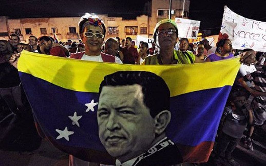 Венесуела, Каракас. Прихильники президента Венесуели Уго Чавеса тримають прапори з його портретами під час участі у мітингу перед військовим госпіталем в Каракасі. Чавес був госпіталізований і зараз проходить третій курс хіміотерапії для лікування раку. / © AFP