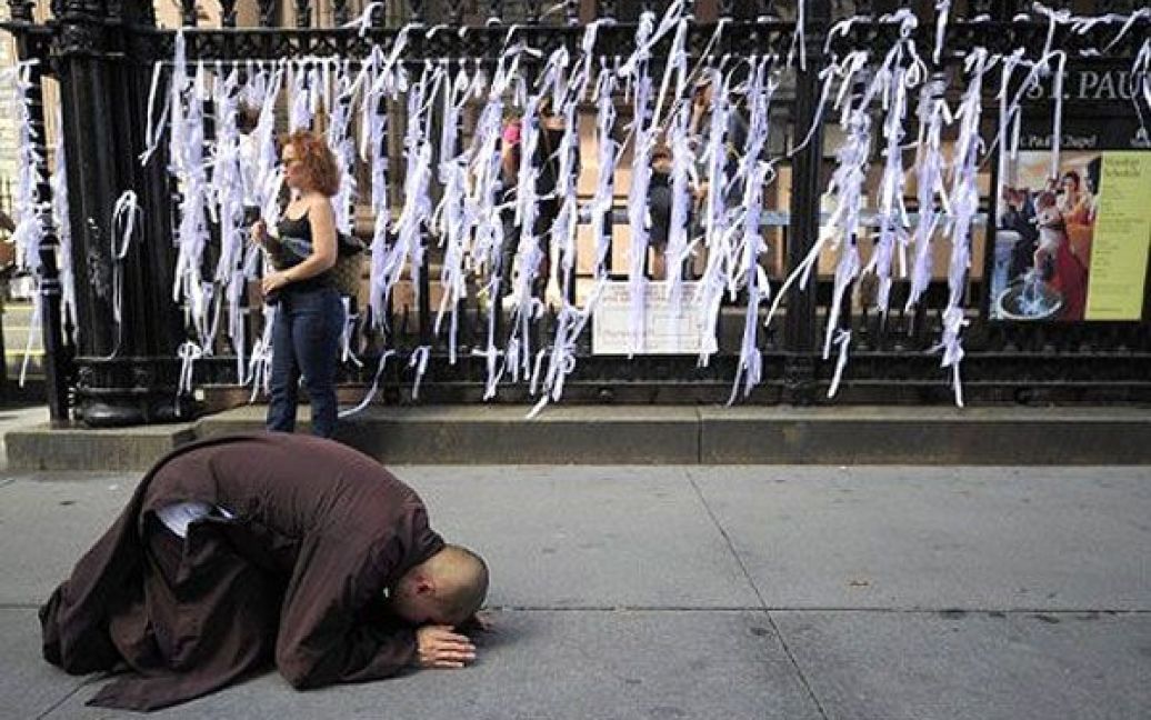 США, Нью-Йорк. Буддійський чернець молиться перед меморіальними "стрічками пам&#039;яті", які перехожі розвішують на паркані каплиці Святого Павла. Люди вшановують пам&rsquo;ять жертв теракту 9/11. Нью-Йорк готується до 10-ої річниці нападу на вежі Всесвітнього торгового центру. / © AFP