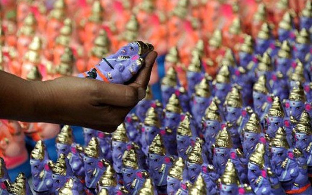 Індія, Бангалор. Індус вибирає глиняну фігурку слона, яка символізує індуїстського бога Ганеша на ринку ідолів у Бангалорі. Індія готується до релігійного фестивалю "Ганеш Чатурті", який проходитиме з 1 по 11 вересня. / © AFP