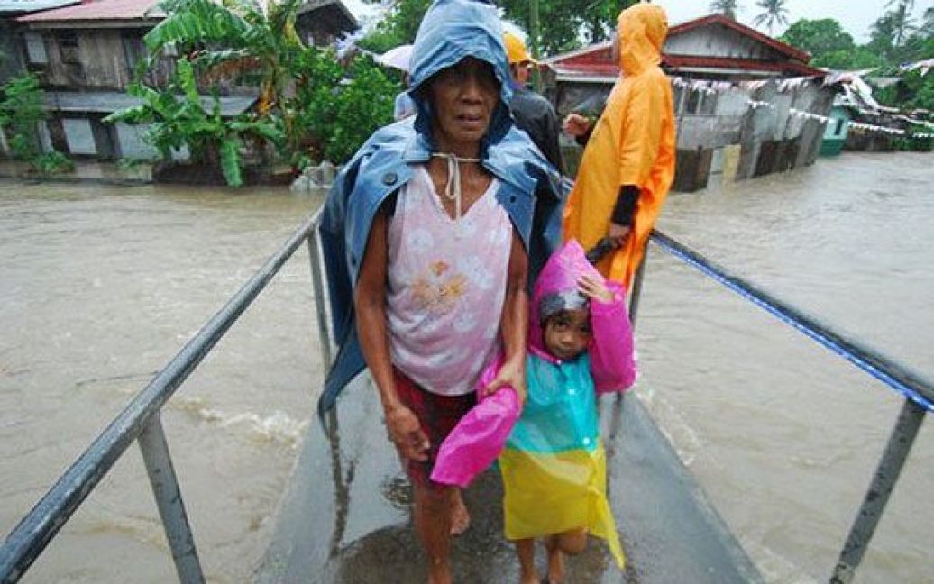 Філіппіни, Легазпі. Місцеві мешканці перетинають тимчасовий дерев&#039;яний міст під час евакуації із затоплених будинків. На Філіппіни обрушився тайфун Несат, більше 100 тисяч мешканців східного узбережжя країни закликали евакуюватись, було закрито школи і скасовано авіарейси. / © AFP