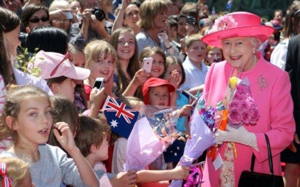 Австралія, Мельбурн. Британська королева Єлизавета II отримує квіти від натовпу під час візиту на площу Федерації в центрі Мельбурна. Британська королева проїхалася у пам&#039;ятному трамвай та зустрілася з місцевими мешканцями. / © AFP