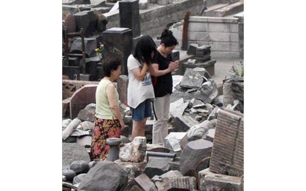 Японія, Оцучі. Жінки моляться на місці загибелі своїх родичів, які стали жертвами цунамі. Уряд Японії має намір розпочати евакуацію жителів міст, що знаходяться у безпосередній близькості від АЕС Фукушіма. / © AFP