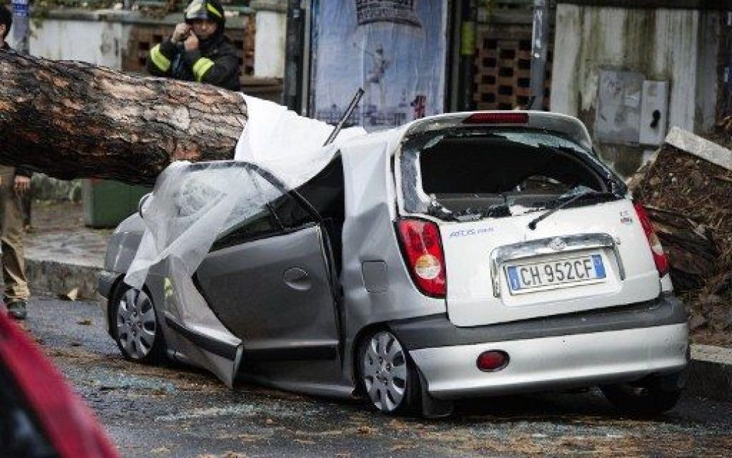 Італія, Арко Феліче. Рятувальники працюють на місці падіння дерева на автомобілі. В результаті потужних злив та штормової погоди на півночі Італії, 6 людей загинули. / © AFP