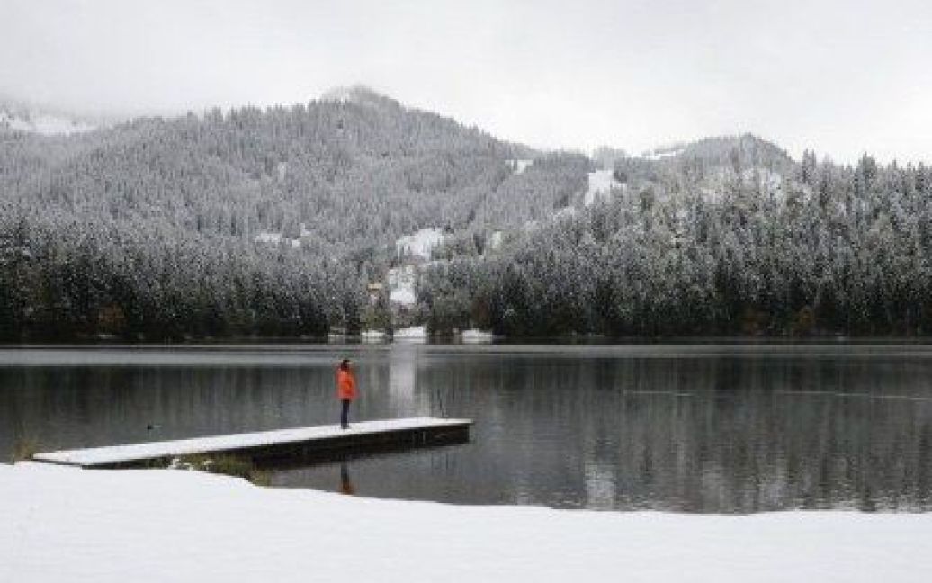 Німеччина, Шпітцингзі. Жінка стоїть перед озером в Альпах на півдні Німеччини після того, як в країні випав перший сніг у сезоні. / © AFP