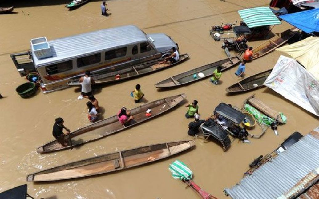 Філіппіни, Кандаба. Жителі пробираються на човнах вулицями міста, затопленого паводковими водами. Головний острів Філіппін Лусон постраждав від удару потужного тайфуну Несат, майже мільйон людей опинився на затоплених територіях. / © AFP