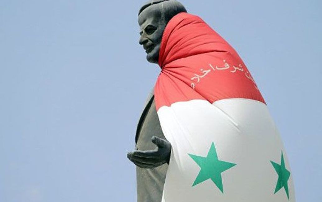 Сирія, Гомс. Національний прапор почепили на статую покійного президента країни Хафеза аль-Асада на в&#039;їзді до міста Хомс, де спалахнули гучні антиурядові протести. / © AFP