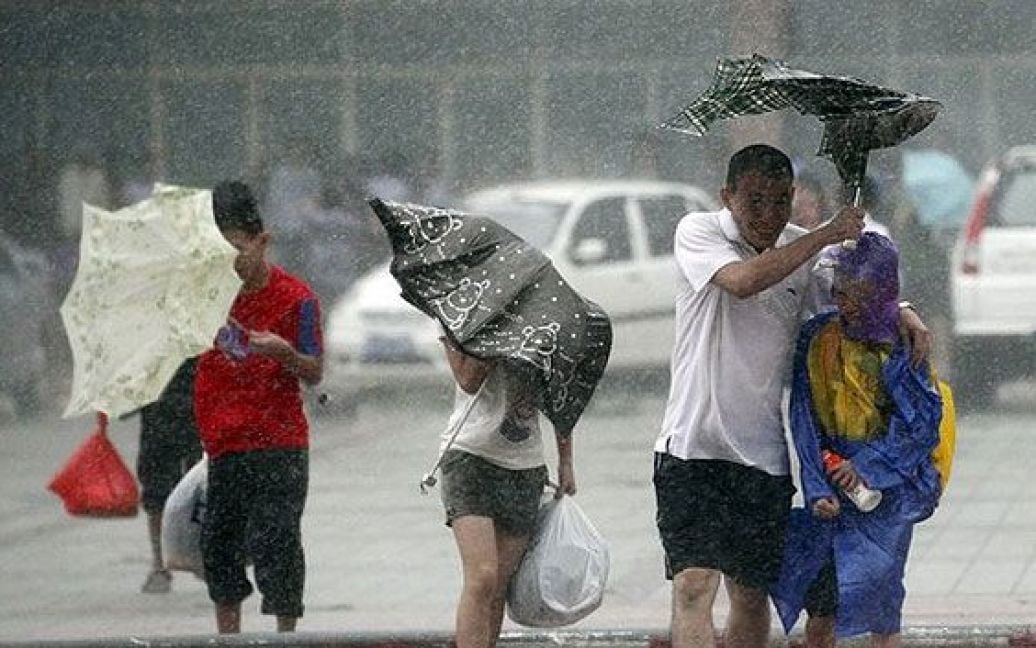 Китай, Хайкоу. Люди пробираються крізь затоплену вулицю міста Хайкоу на острові Хайнань. Потужний тайфун Несат &mdash; найсильніший тайфун у Китаї за цей рік &mdash; обрушився на острів Хайнань. Більше 100 тисяч людей були евакуйовані. / © AFP