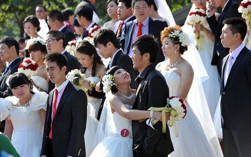 Китай, Пекін. Двадцять одна пара закоханих взяла участь у масовій весільній церемонії в парку Хайдянь у Пекіні. / © AFP