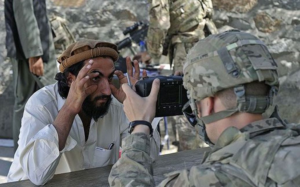 Афганістан, Туркхам. Солдат американської армії сканує очі афганця за допомогою автоматизованої біометричної ідентифікаційної системи під час операції в районі Нангархар на межі з Пакистаном. / © AFP