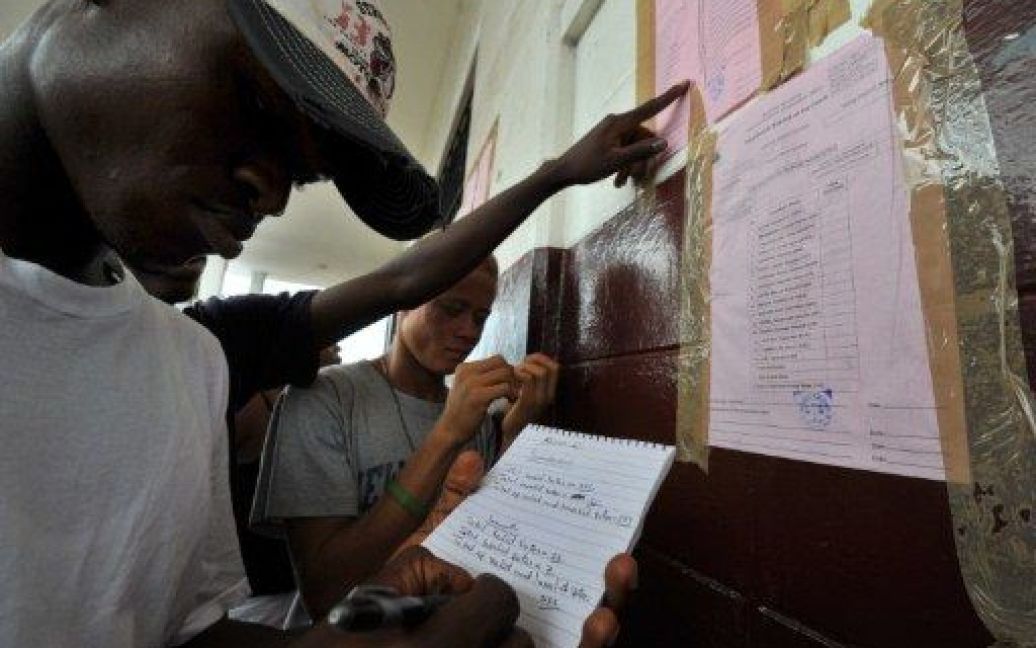 Ліберія, Монровія. Люди перевіряють активність виборців перед приміщенням для голосування в місті Монровія. В Ліберії провели другі повоєнні вибори. / © AFP