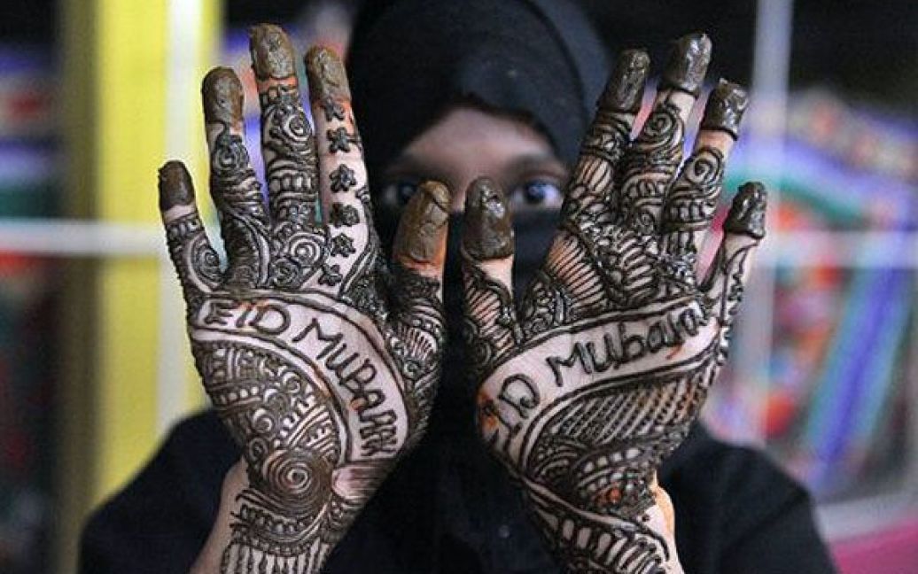 Індія, Хайдарабад. Індійська мусульманка показує руки, прикрашені малюнком мехенді (хною), під час святкування "Чанд Раат" ("Ніч Місяця") в Хайдарабаді. Мусульмани у всьому світі почали святкувати Ід-аль-Фітр, закінчення священного місяця Рамадан. / © AFP