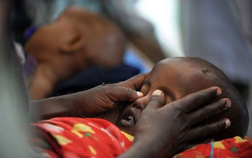 Сомалі, Могадішо. Мати кладе монети на очі своєму дворічному сину Махмуду, який  помер від недоїдання та ускладнень у місцевій лікарні. Близько 12 мільйонів людей в Ефіопії, Джибуті, Кенії, Уганді і Сомалі перебувають під загрозою голоду через найсильнішу за останні десятиліття посуху в регіоні. / © AFP