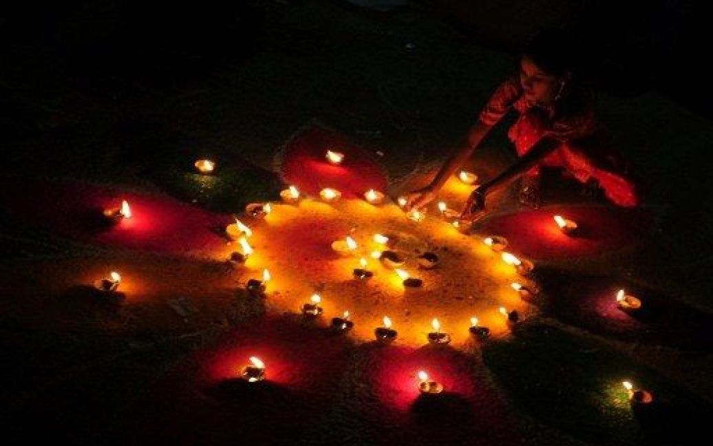 Пакистан, Карачі. Пакистанська жінка запалює вогні ламп під час святкування Дівалі. Дівалі, свято вогнів та світла, є одним з найбільших фестивалів у індусів. / © AFP