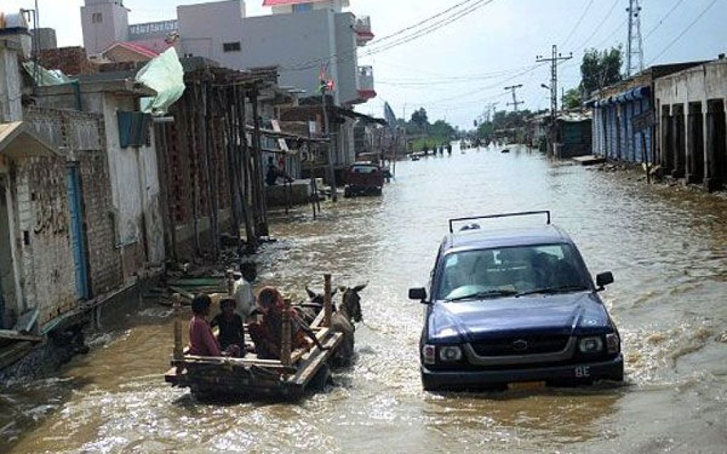 Пакистан, Бадін. Пакистанці на віслюку їдуть вулицею, затопленою в результаті повені у Бадіні. Повені, викликані мусонними дощами, призвели до загибелі майже 350 осіб, більше 7 мільйонів людей постраждали або залишились без даху над головою. / © AFP