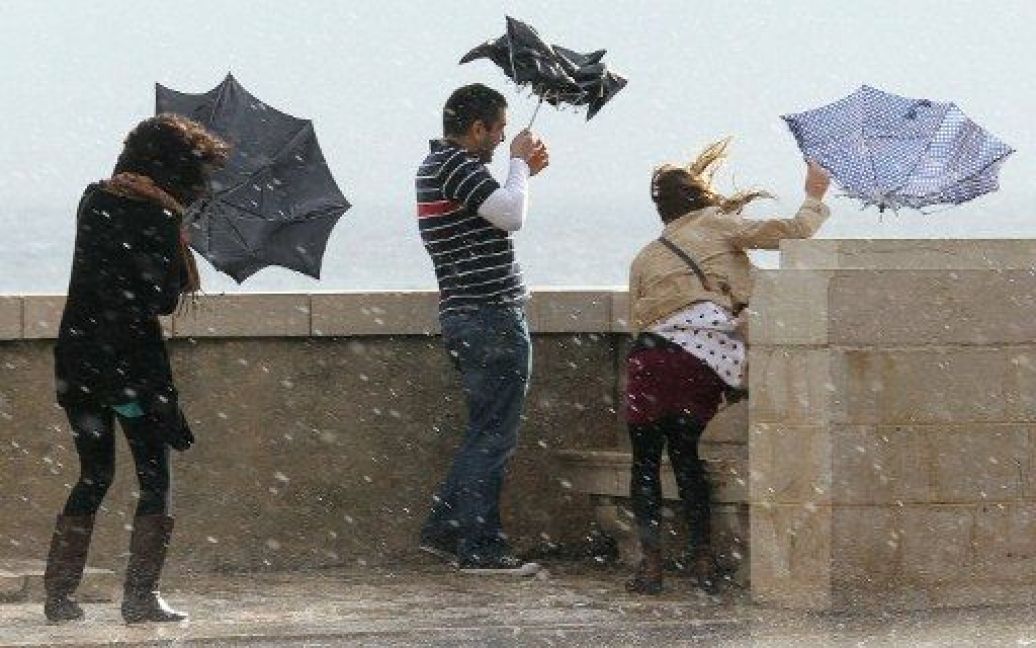 Франція, Ніцца. Люди намагаються втримати свої парасольки під час сильного вітру на узбережжі французької Рів&#039;єри. Південь Франції постраждав від поганих погодних умов, проливних дощів. / © AFP