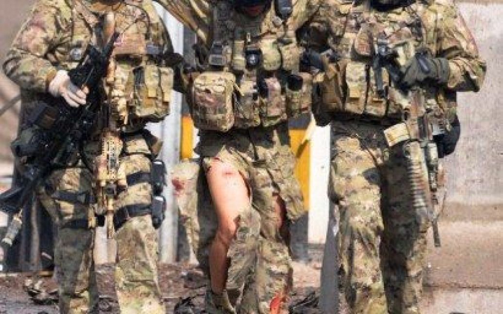 Афганістан, Герат. Солдати очолюваних НАТО міжнародних сил сприяння безпеці допомагають своєму товаришу, який отримав поранення під час перестрілки з нападниками на околиці міста Герат. / © AFP