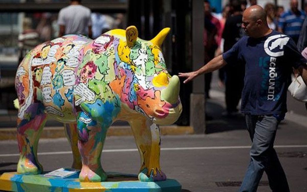 Бразилія, Сан-Паулу. Чоловік роздивляється фігуру носорога, виготовлену зі скловолокна, яку встановили на одній з вулиць Сан-Паулу в рамках арт-проекту "Rhino Mania". На вулицях міста розставили 60 фігур носорогів, створених місцевими художниками. / © AFP