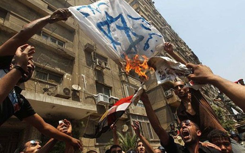 Єгипет, Каїр. Єгипетські демонстранти спалюють ізраїльський прапор під час акції протесту перед посольством Ізраїлю в Каїрі. Єгипет прийняв рішення відкликати свого посла з Ізраїлю на знак протесту проти загибелі поліцейських на кордоні під час першої дипломатичної суперечеки між двома країнами з часу падіння режиму Мубарака. / © AFP