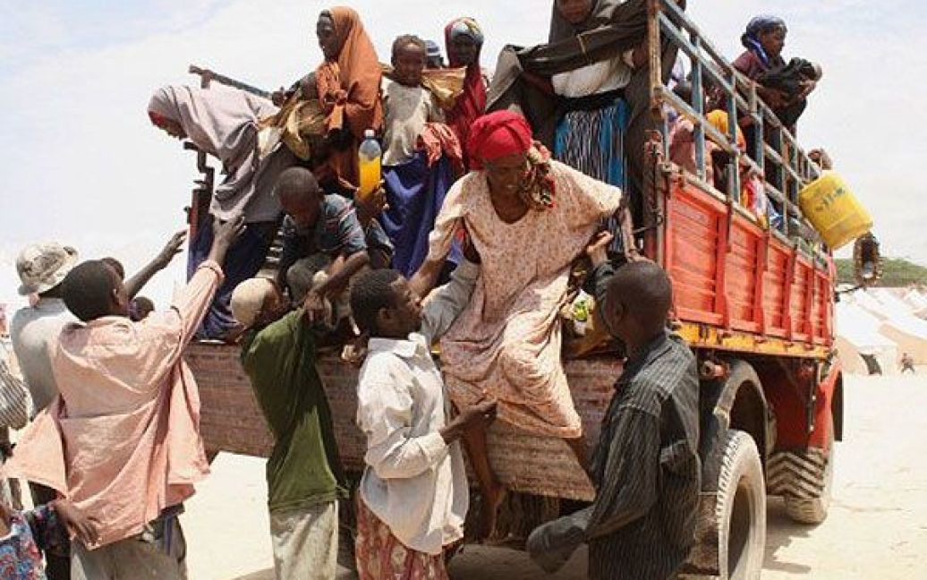 Сомалі, Могадішо. Чоловіки допомагають членам своїх родин, які постраждали від голоду, після прибуття до табору для внутрішньо переміщених осіб у південній частині Могадішо. Голод починає поширюватися на два нових регіони Сомалі. / © AFP