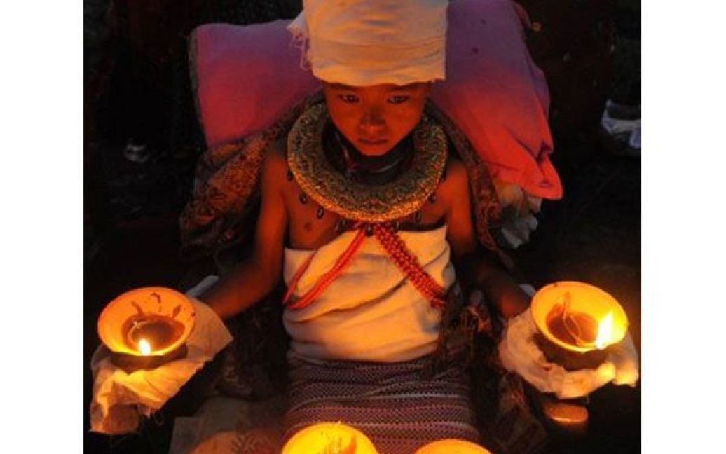 Непал, Бхактапур. Хлопчик, який протягом шести годин втримував на голові, руках та ногах палаючі масляні лампи та пальмові гілки під час церемонії на найбільшому святі індусів, Дурга Пуджа. / © AFP
