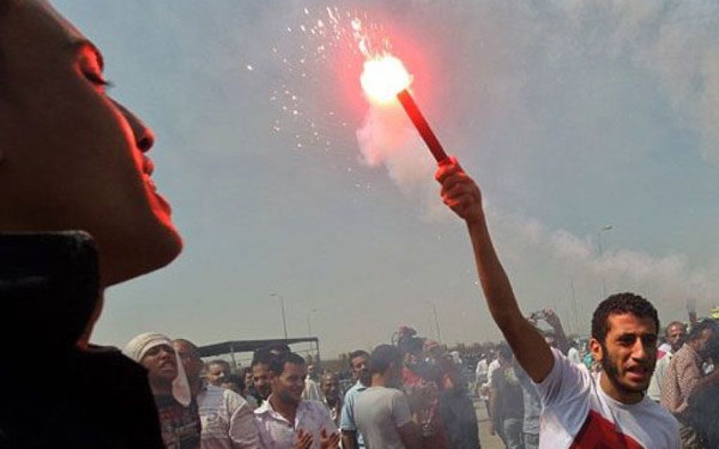 Єгипет, Каїр. Єгипетські антиурядові демонстранти, які виступають проти Хосні Мубарака, запалюють димові шашки поблизу поліцейської академії, де відновився суд над поваленим президентом Хосні Мубараком. / © AFP