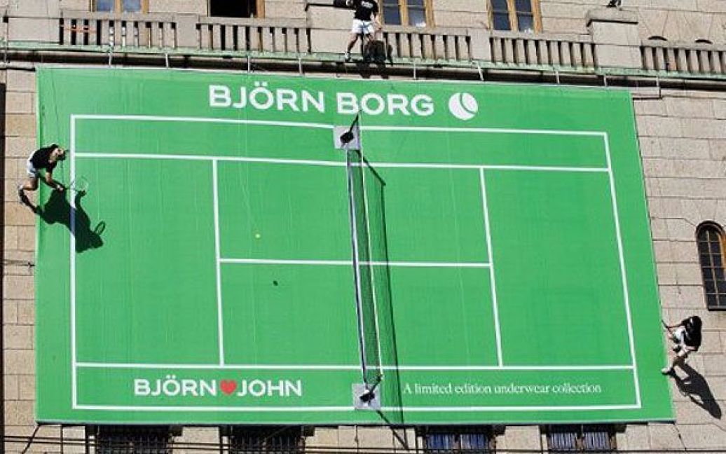 Швеція, Стокгольм. Шведи у костюмах колишніх міжнародних гравців у теніс, американця Джона Макінроя та шведа Бьорна Борга, грають в теніс на фасаді універмагу NK в Стокгольмі. / © AFP