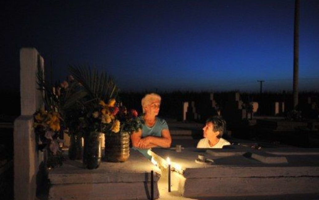 Куба, Мелена дель Сур. Жінка сидить поруч із могилою свого родича на кладовищі в Мелена-дель-Сур. На Кубі відзначають католицьку дату &mdash; День мертвих. / © AFP