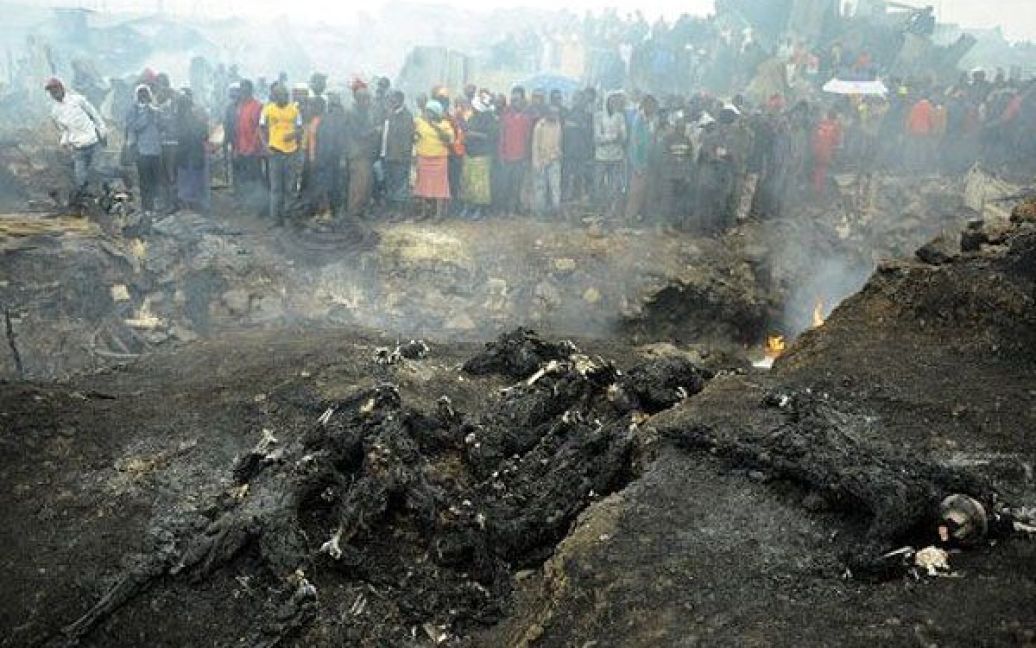 Кенія, Найробі. Мешканці нетрів у Найробі збираються навколо обвуглених тіл, що лежать на місці вибуху трубопроводу. В результаті загоряння трубопроводу і вибуху палива у нетрях Найробі, принаймні, 120 осіб згоріли. / © AFP