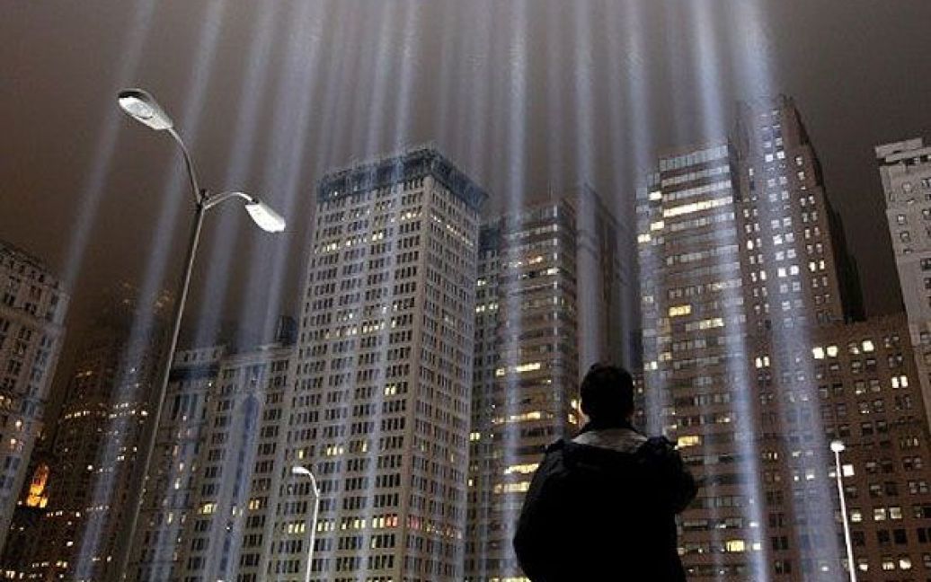 США, Нью-Йорк. Працівник дивиться на струмені світла, з яких встановили меморіал жертвам терористичних атак 11 вересня в Нью-Йорку. Меморіал складається з 88 потужних 7000 Вт прожекторів, які закріпили на місці Всесвітнього торгового центру. / © AFP