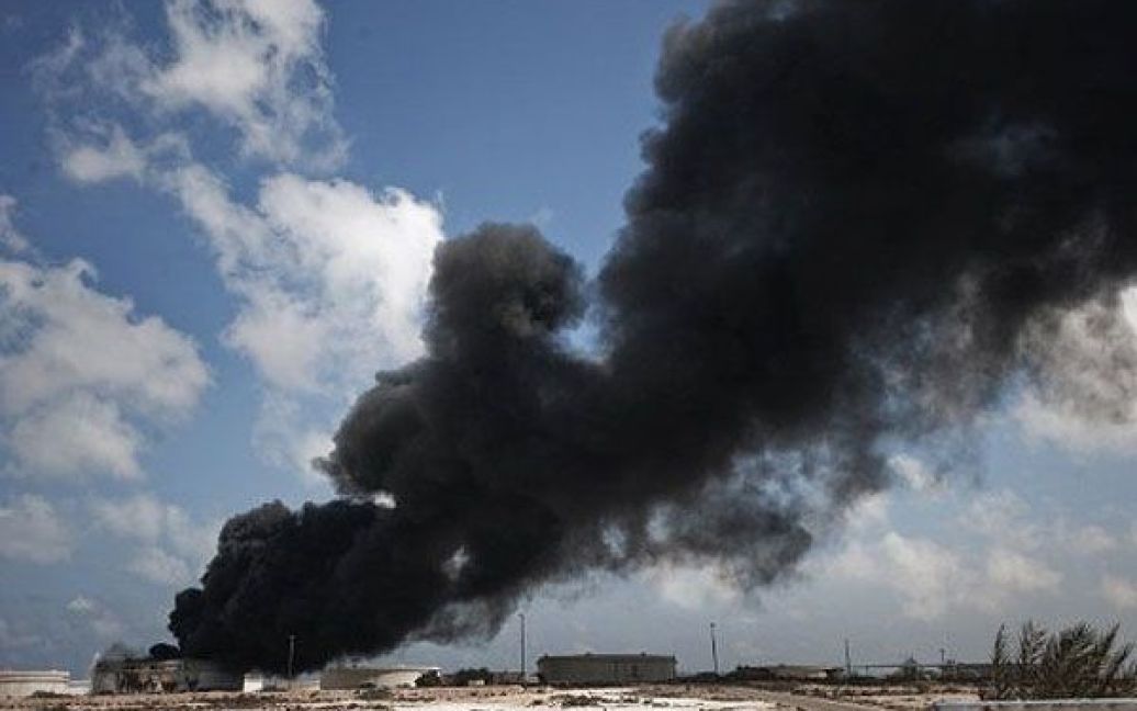 Лівійська Арабська Джамахірія, Брега. Чорний дим піднімається над нафтохімічною установкою в місті Брега. В країні тривають бойові дії між силами повстанців і прихильниками лідера країни Муаммара Каддафі. / © AFP