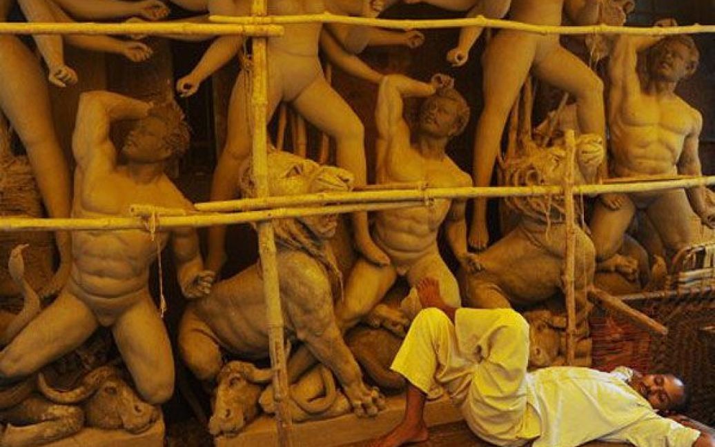 Індія, Калькутта. Індус лежить поруч з фігурами глиняних статуй індуїстської богині Дурги. Мусонні дощі ускладнюють роботу ремісників, які готують ідолів до індуїстського фестивалю Пуджа Дурга, який відзначатимуть в жовтні. / © AFP