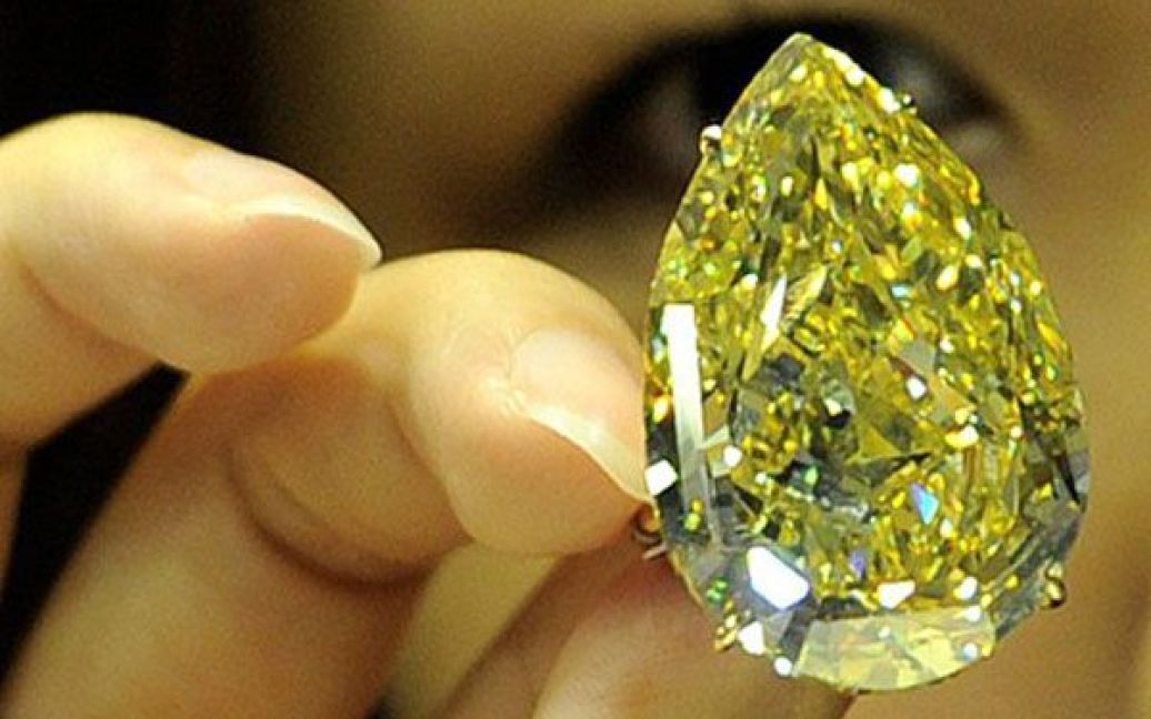 Китай, Гонконг. Співробітник аукціону Сотбіс демонструє алмаз "Сонячна крапля", оцінений у 110,03 карата. Незвичайний яскраво-жовтий алмаз буде проданий з аукціону за кошторисною вартістю від 11 до 15 мільйонів доларів США. / © AFP