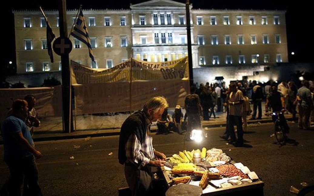 Греція, Афіни. Вуличний торговець продає варену кукурудзу таксистам, які влаштували акцію протесту перед будівлею грецького парламенту. Таксисти провели в Афінах черговий 48-годинний страйк. / © AFP