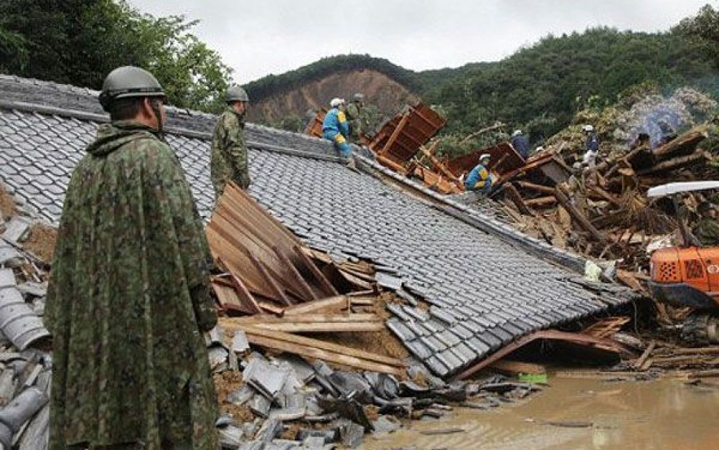 Японія, Танабе. Рятувальники і солдати сил самооборони Японії шукають зниклих безвісті під будинком, зруйнованим повінню, у місті Танабе, префектура Вакаяма. В результаті тайфуну Талас, який приніс проливні дощі та сильні вітри на захід Японії, щонайменше 17 людей загинули, 43 зникли безвісті. / © AFP