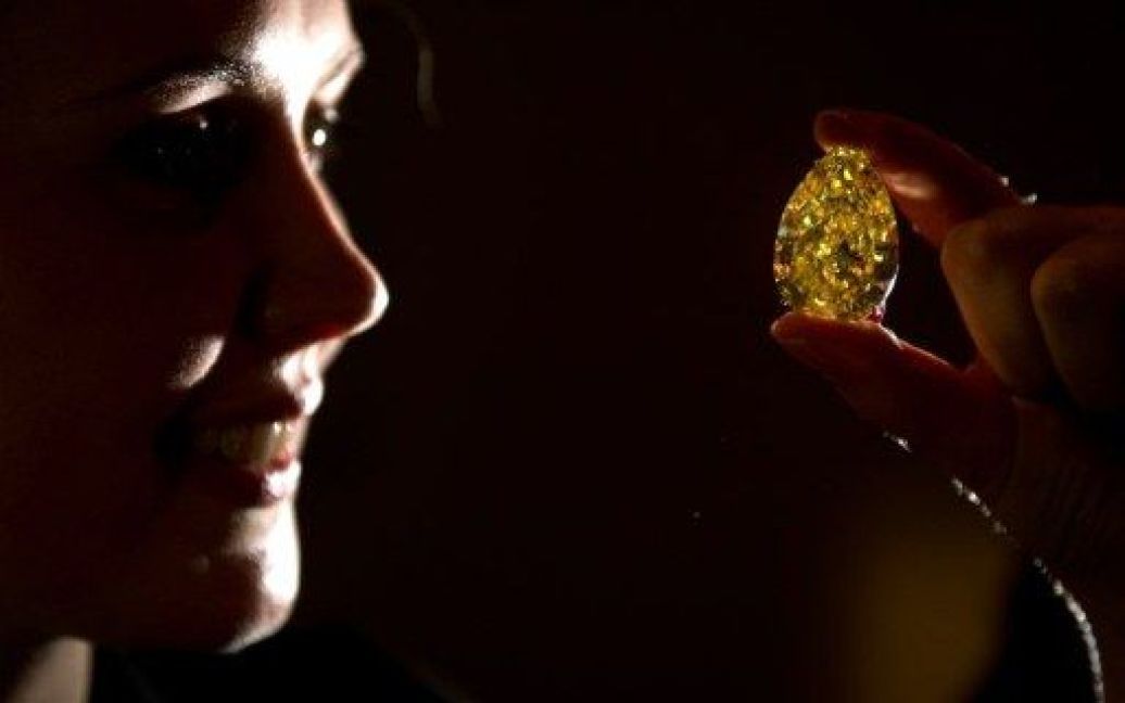 Великобританія, Лондон. Співробітник аукціону тримає діамант "Sun-Drop Diamond" ("Сонячна крапля") під час показу в аукціонному будинку Сотбіс у Лондоні. Діамант у 110,3 карата буде виставлений на аукціон в листопаді як частина колекції "Дивовижні коштовності" за стартовою ціною 11-15 млн дол. США. / © AFP
