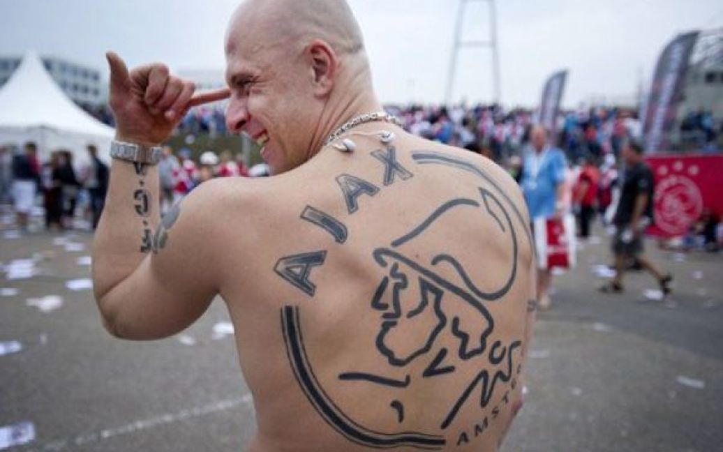 Нідерланди, Амстердам. Фанат футбольного клубу "Аякс" демонструє своє татуювання з логотипом улюбленої команди під час дня відкритих дверей на базі клубу. / © AFP