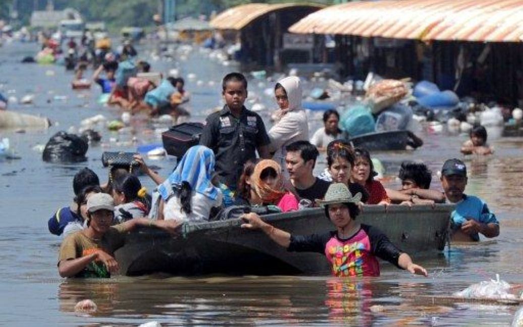 Таїланд, Патхумтхані. Поліція та працівники рятувальних служб допомагають місцевим мешканцям під час евакуації через затоплені вулиці передмістя Бангкоку, провінція Патхумтхані. В результаті трьох місяців сильних мусонних дощів, було пошкоджено тисячі будинків, мільйони людей постраждали. / © AFP