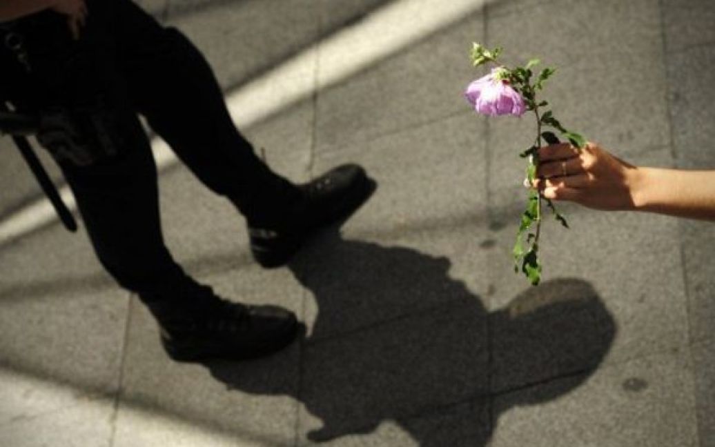 Іспанія, Мадрид. Учасник акції протесту дарує квітку солдату спецназу під час мітингу. Напередодні муніципальних виборів Мадрид охопили численні акції протесту. / © AFP
