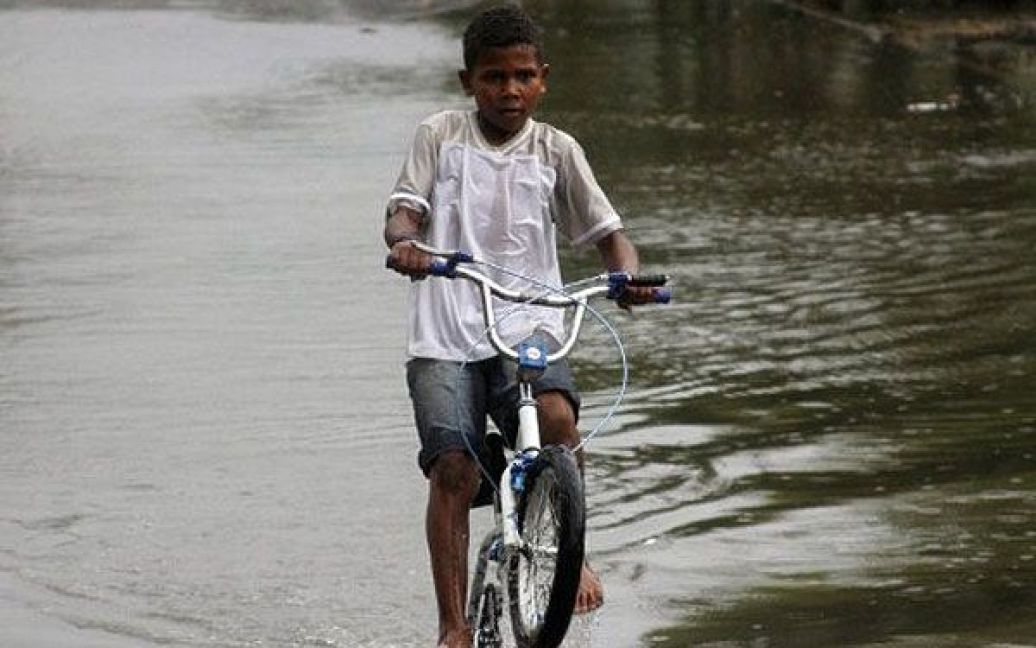 Домініканська Республіка, Санто-Домінго. Хлопчик на велосипеді їде затопленою вулицею міста Санто-Домінго. Країна чекає на неминучий ураган Ірен, який наближається до північного узбережжя в напрямку острова Еспаньола. / © AFP