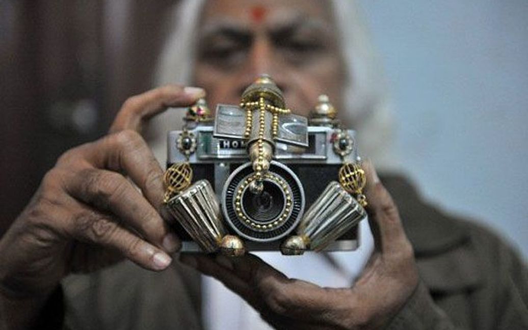 Індія, Хайдарабад. Індійський лікар показує фігуру індуїстського бога Ганеша, виготовлену у вигляді фотокамери та представлену на виставці у Хайдарабаді. / © AFP