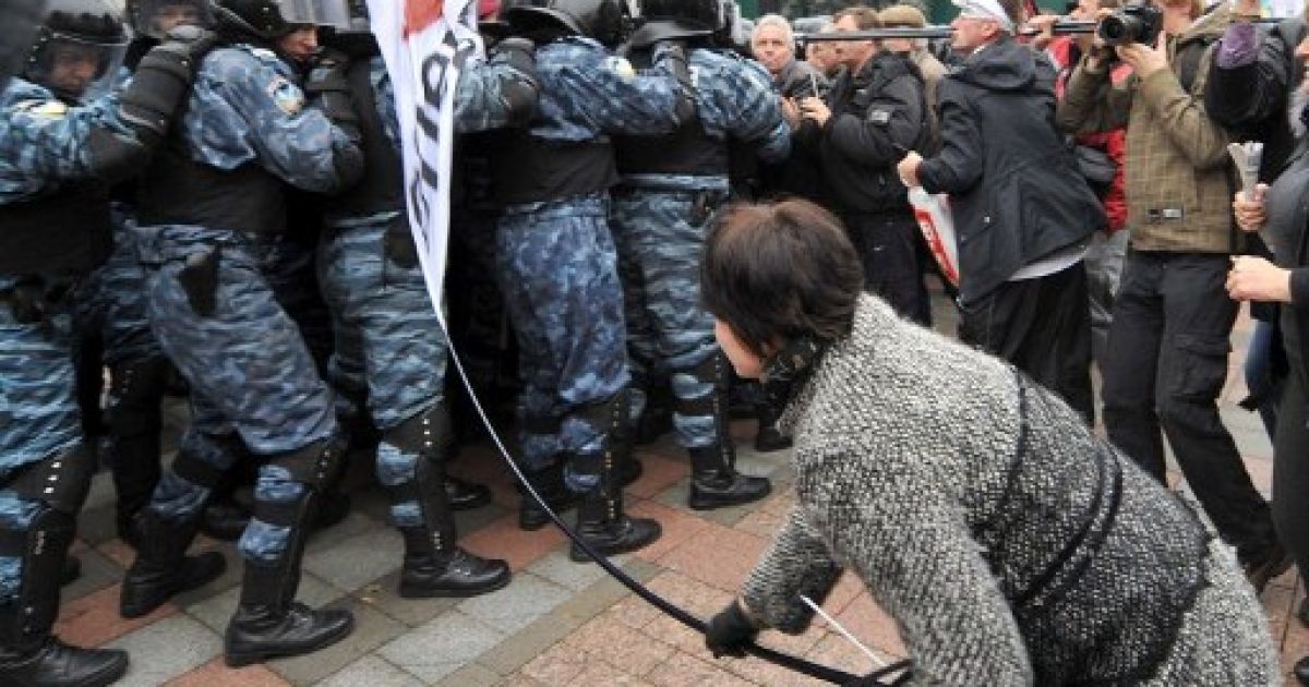 Україна, Київ. Учасниця акції протесту лупцює співробітника "Беркуту" під час сутичок з правоохоронцями  перед українським парламентом. / © AFP