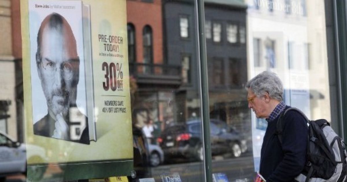 США, Вашингтон. Людина роздивляється плакат із рекламою біографічної книги засновника компанії Apple Стіва Джобса, виставлений на вітрині книжкового магазина в Джорджтауні у Вашингтоні. / © AFP