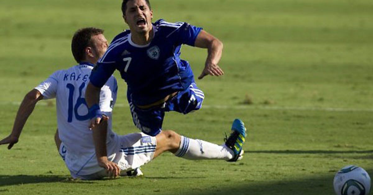 Ізраїль, Тель-Авів. Гравець збірної Греції Пантеліс Кафес падає на землю після зіткнення з півзахисником збірної Ізраїлю Берамом Каялом під час матчу відбіркового туру чемпіонату Євро-2012. / © AFP